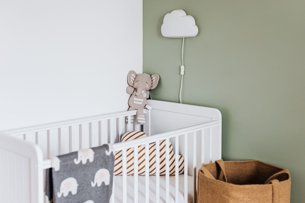 Modern nursery with a white travel crib and soft decor