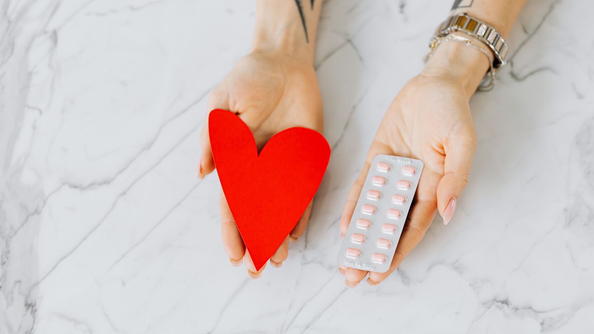 Modafinil and Kidney Health: Exploring the Connection Close-up of hands holding a red heart shape and a blister pack of pills on a marble surface — modafinil and kidney health