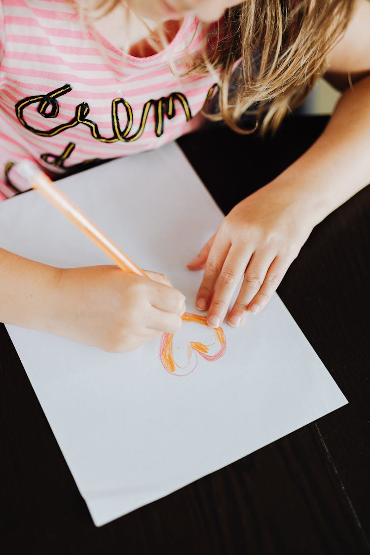 Girl Drawing A Heart On Paper