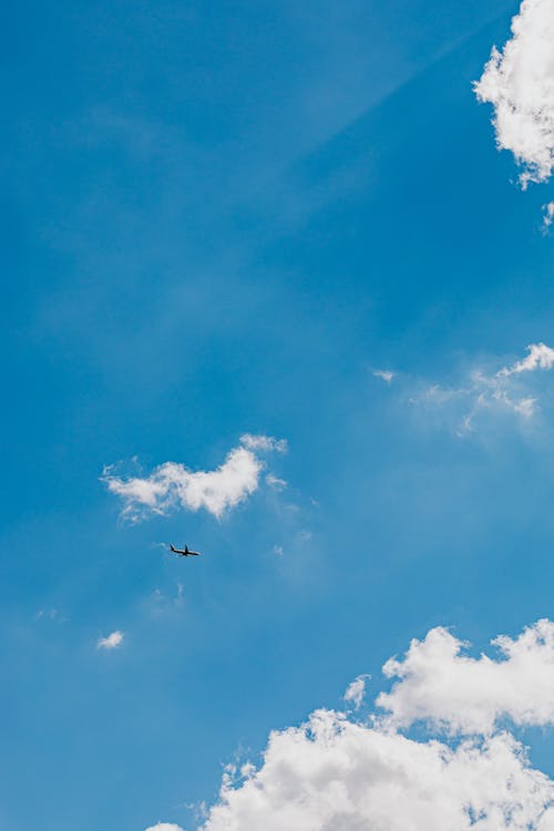 Airplane in Mid Air Under Blue Sky and White Clouds