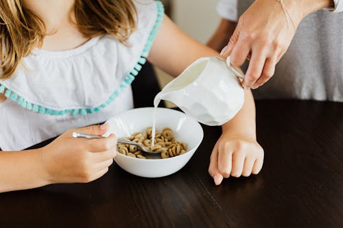 
Woman Pouring Milk on a Bowl with Cereals
