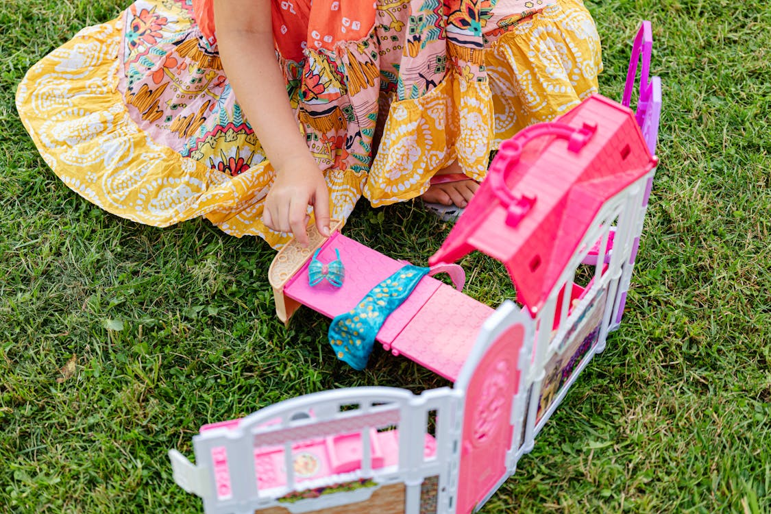 Free Girl in Floral Dress Playing Mini Bedroom Toy Stock Photo