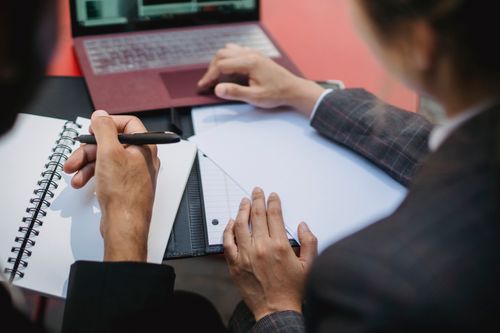 Free Two people working together with a laptop and notebook, focusing on writing and planning. Stock Photo