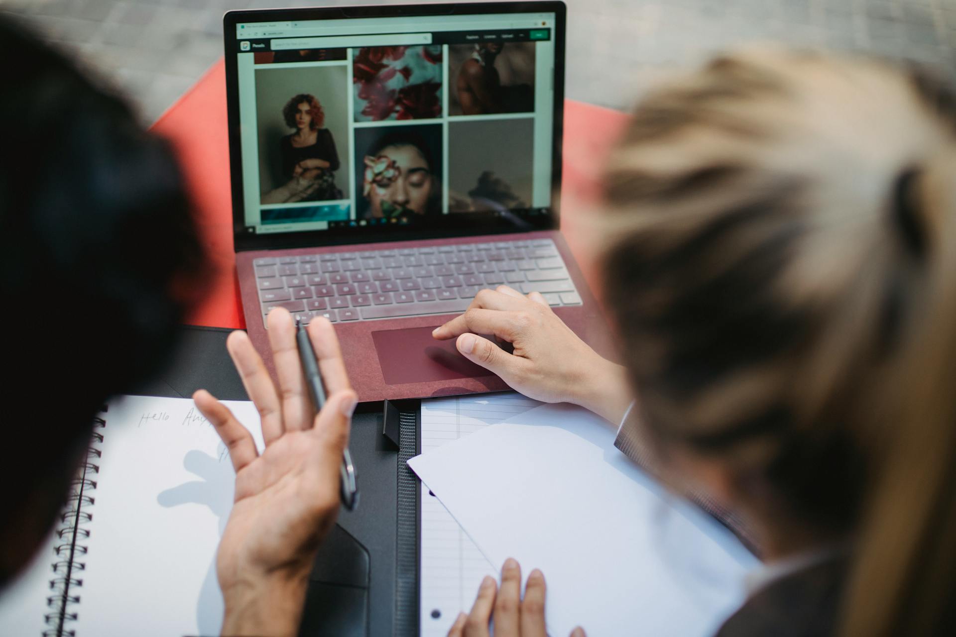 Two people collaborating over a laptop and notes, discussing creative ideas.