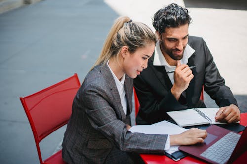 Man and Woman Discussing in front of a Laptop