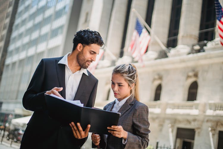 Man And Woman In Formal Attire Looking At The Papers