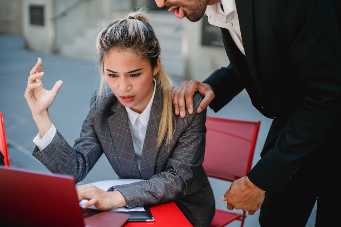 Two professionals engaged in an intense discussion outdoors using a laptop