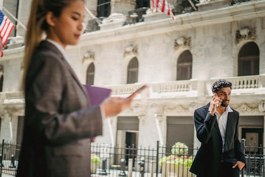 Business professionals in suits using smartphones outside a grand building.