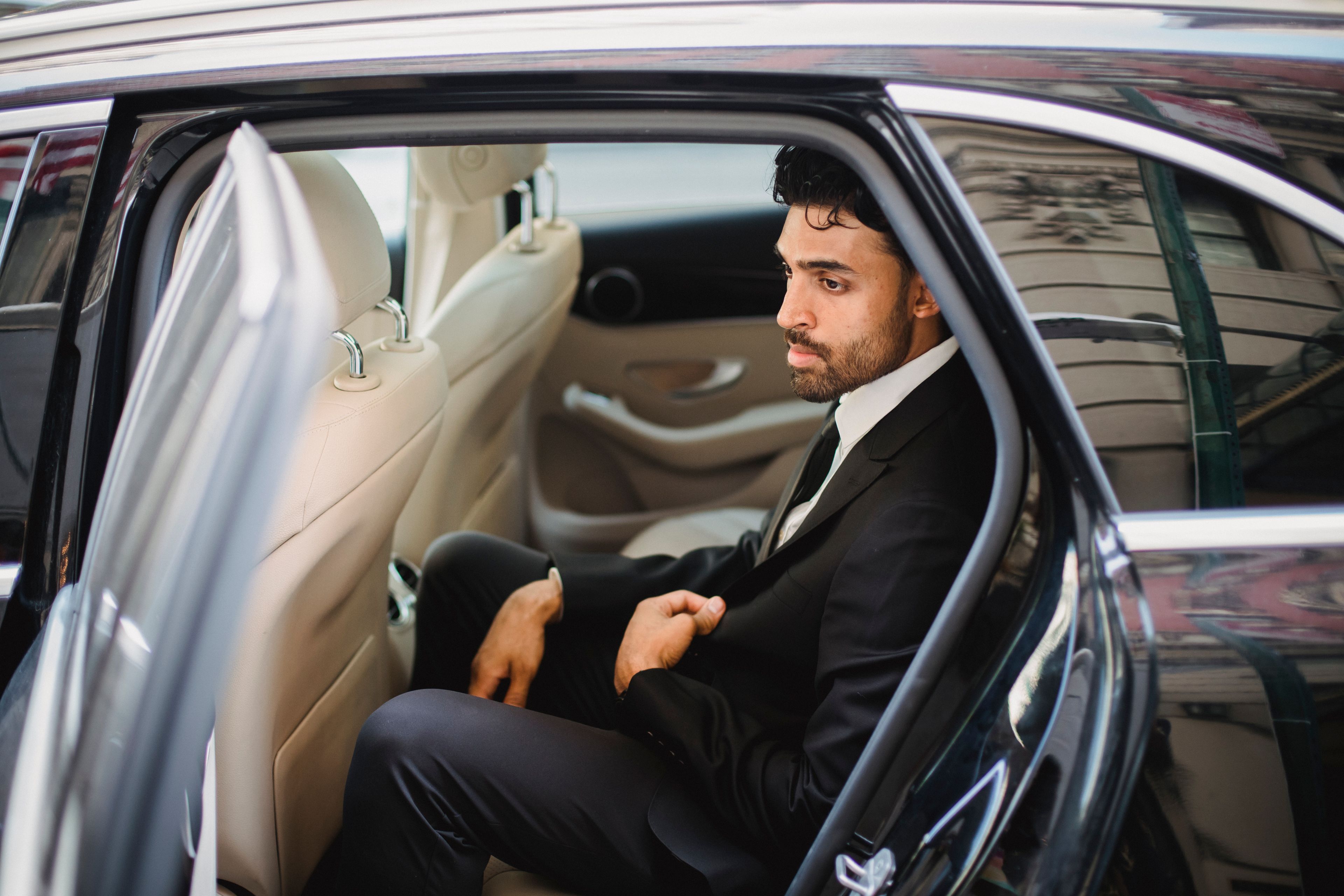 A professional chauffeur waiting beside a luxury car