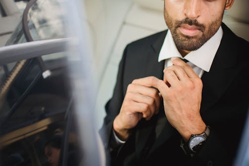 Man in Black Suit Holding His Necktie