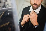 一位穿着黑色西装的优雅男士调整着领带，散发出自信与风度