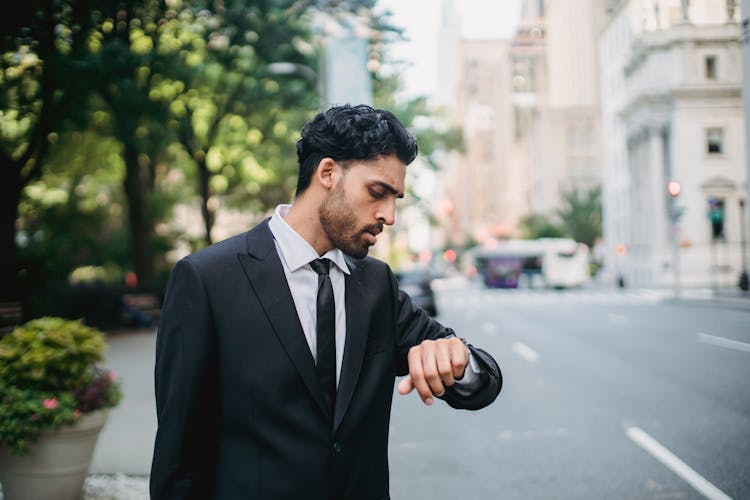 Man In Black Suit And Tie Looking At Wrist