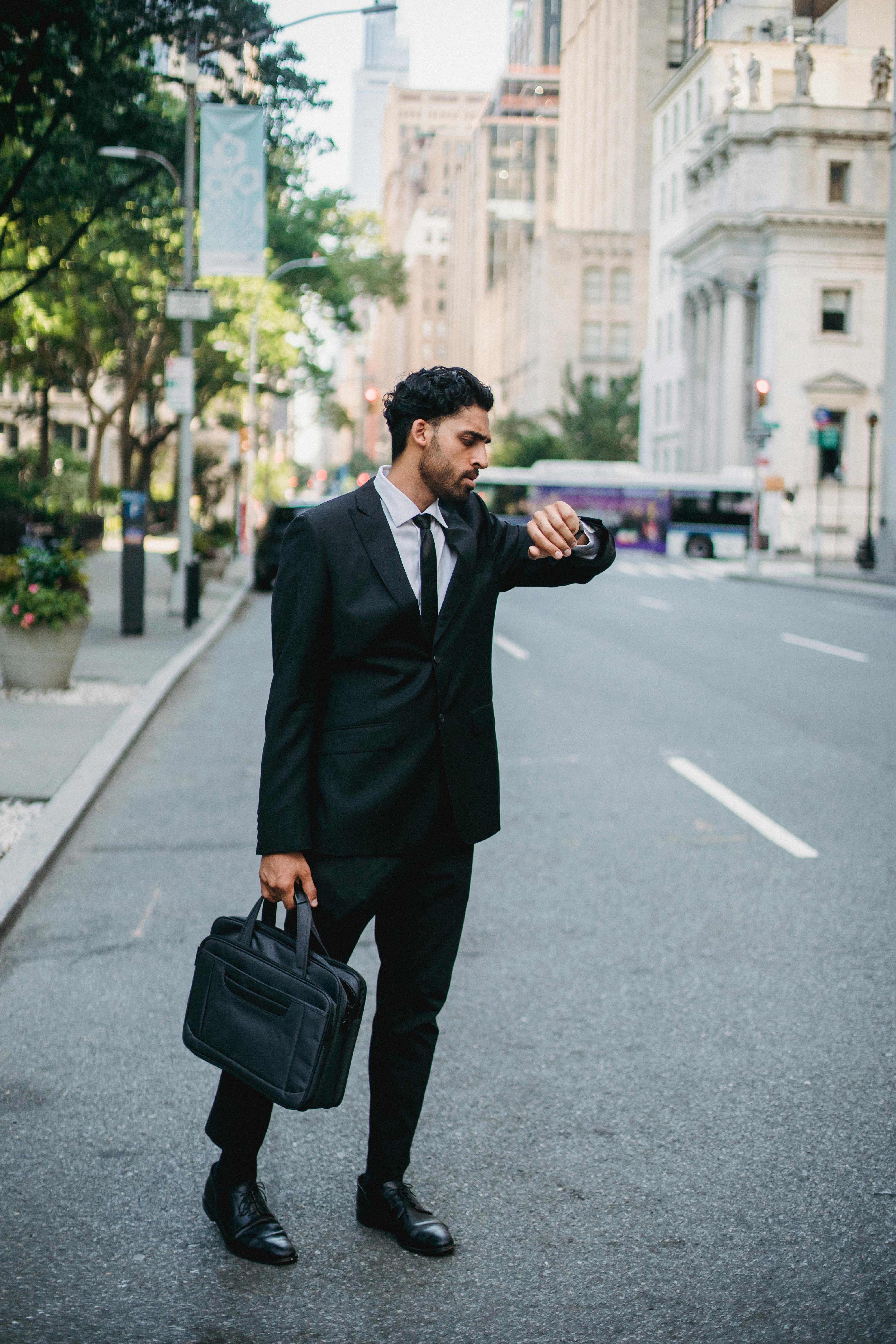 Man in Black Suit Holding Black Leather Bag Standing on Street · Free
