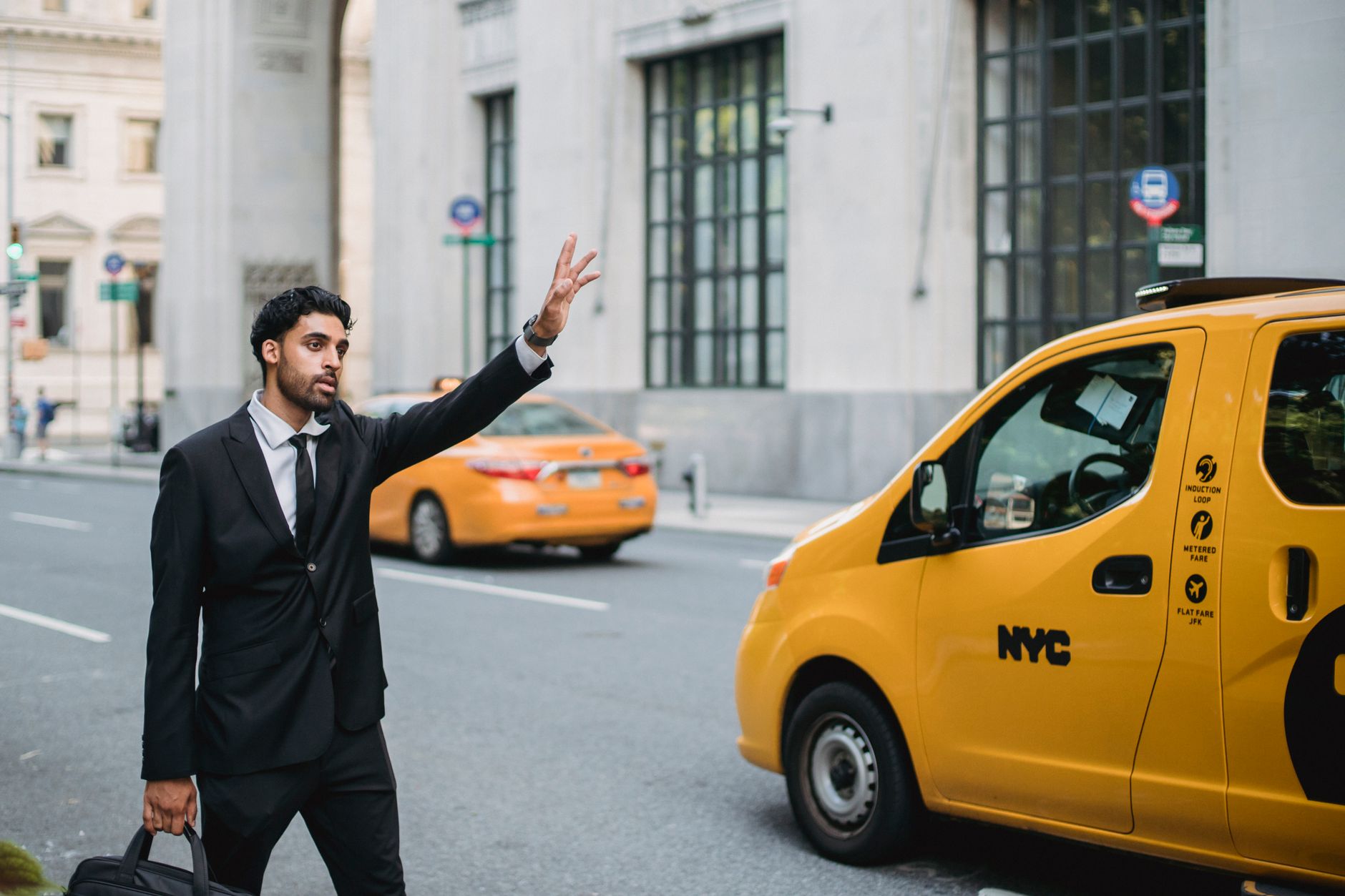 Business professional hailing a taxi on a busy New York City street. Vibrant city life.