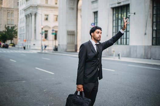 Businessman in formal attire hailing a taxi on a city street with elegant architecture.