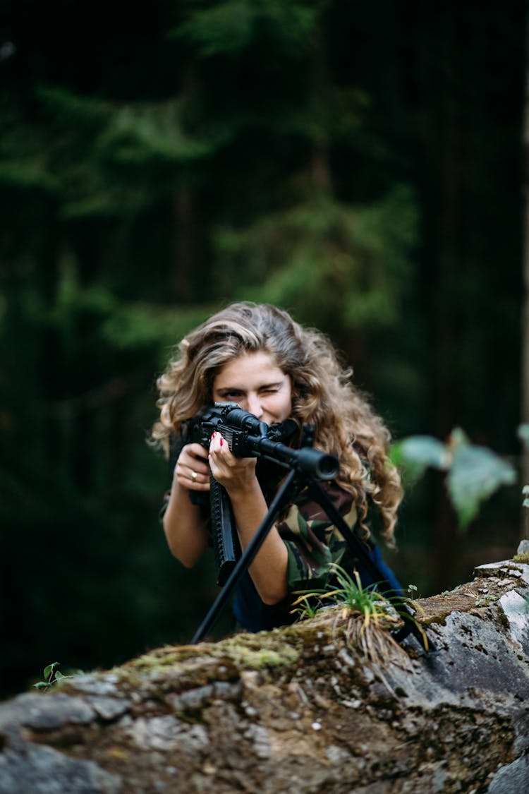 Woman With Long Curly Hair Winking On A Firearm