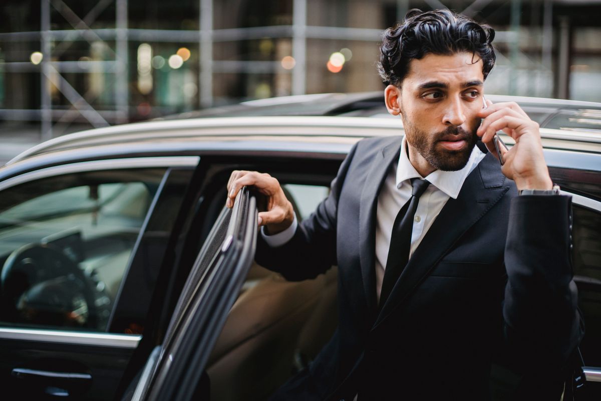 Businessman in a suit stepping out of a chauffeured car