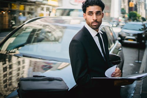 Man in Black Suit Leaning on His Car