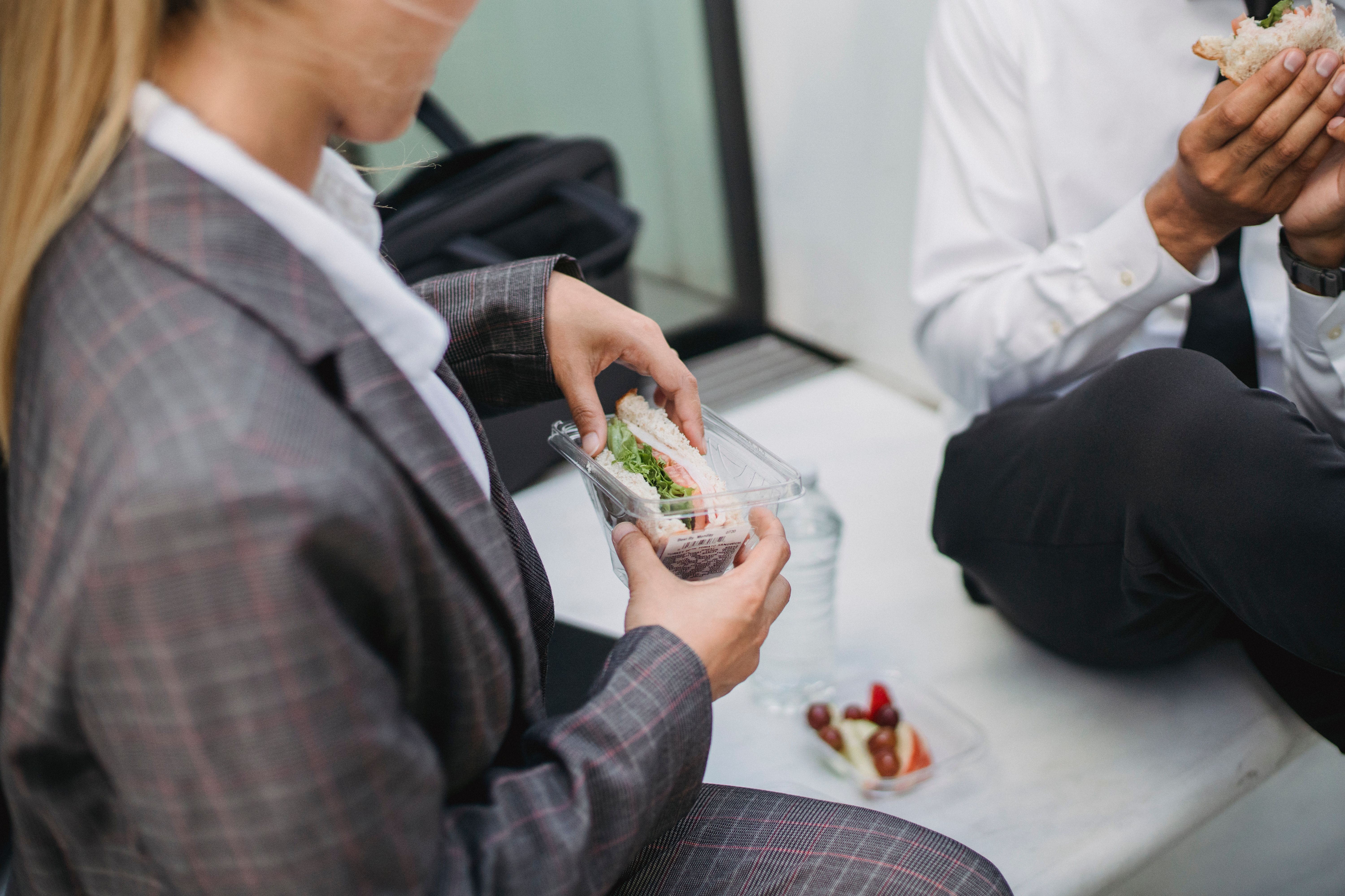 午休时间，两名身着职业装的专业人士正在享用三明治，完美诠释了办公室与生活方式的主题