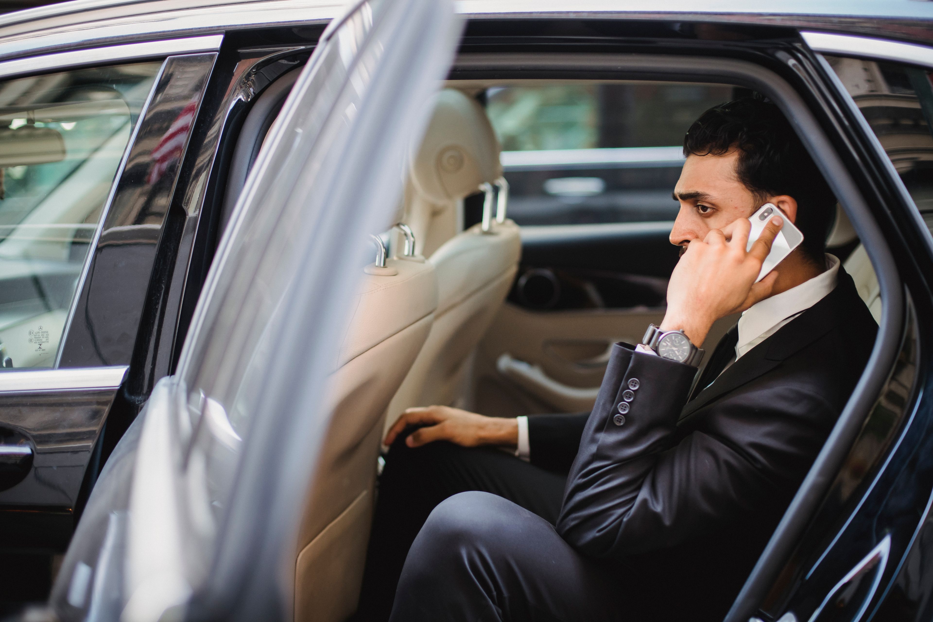 A professional chauffeur waiting beside a luxury car