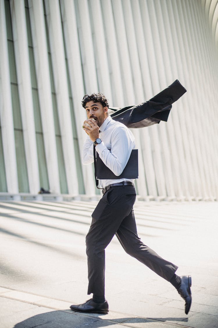 
A Man In A Corporate Attire Eating While Walking