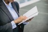 A Woman in a Blazer Reading from a Notebook