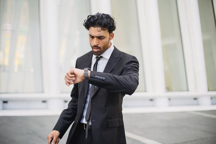 

A Bearded Man In A Suit Looking At His Watch