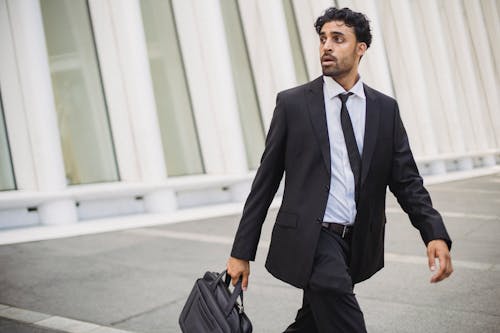 

A Bearded Man in a Suit Holding a Briefcase while Walking