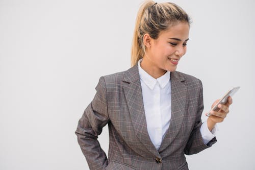 

A Woman in a Plaid Suit Using Her Smartphone