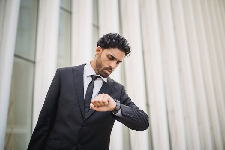 
A Bearded Man In A Suit Looking At His Watch