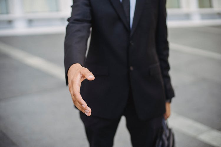 

A Man In A Suit With His Hand Out For A Handshake