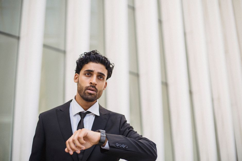 A professional man in a suit checks the time on his watch while standing outside, capturing a business theme. A professional man in a suit checks the time on his watch while standing outside, capturing a business theme.