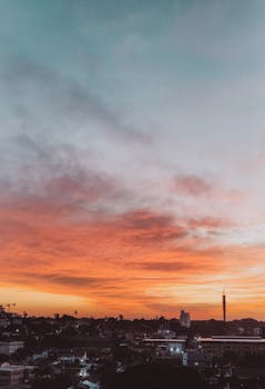 Stunning urban skyline captured during sunset with dramatic clouds and vibrant colors.