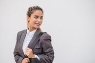 一位自信的女人穿着格子西装外套，背着包，在白色背景下回头张望