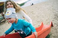 Girl in Blue Long Sleeve Shirt Sitting on Red Plastic Slide