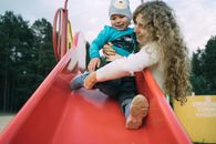 Boy in Blue and White Sweater Sitting on Red Plastic Slide