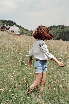 A young woman spins joyfully in a vibrant summer meadow, embracing freedom and nature.