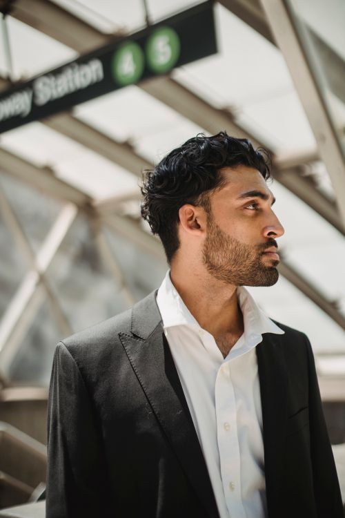 Free Businessman in black suit standing at a metro station with modern architecture. Stock Photo