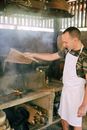 Man in White Apron Holding Brown Wooden Chopping Board