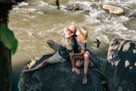 一对夫妇坐在河边岩石上，享受着大自然中流淌的宁静时刻