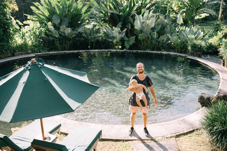 Happy Father With Baby At Resort Swimming Pool