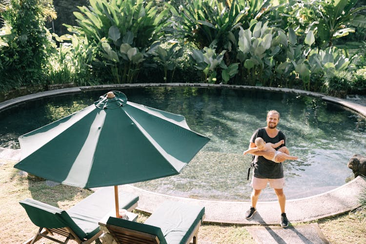 Man Holding Baby By Pool