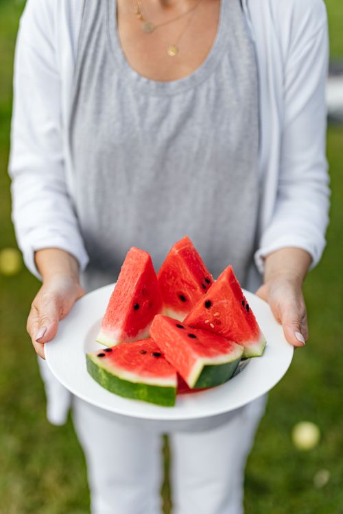 Free A person holding a plate of fresh sliced watermelon in an outdoor setting, perfect for summer vibes. Stock Photo