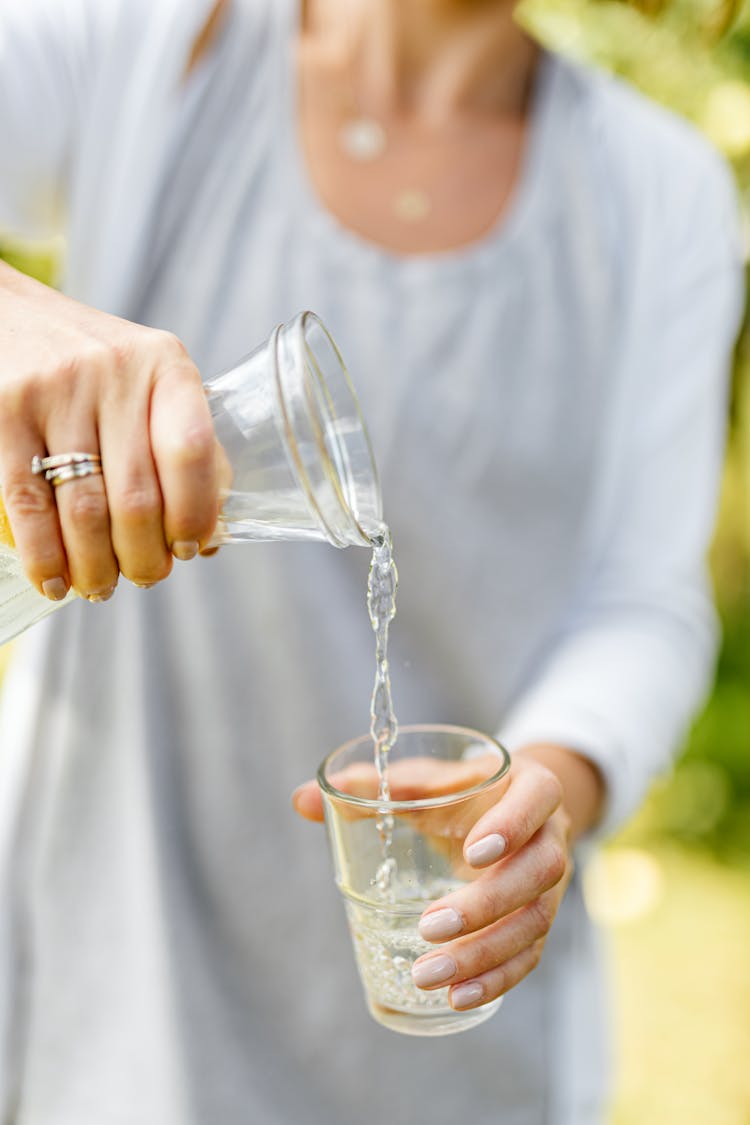 Woman Pouring Water On A Clear Glass