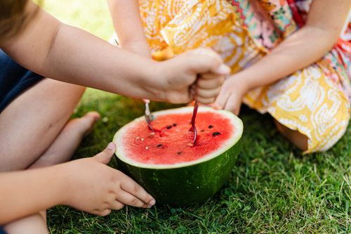 Free Two children sharing a fresh watermelon outdoors on a sunny day, enjoying a healthy snack together. Stock Photo