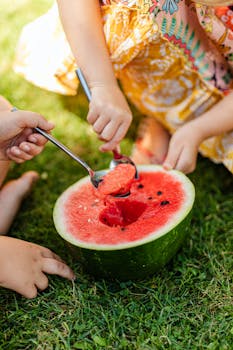 孩子们在阳光明媚的日子里舀着新鲜的西瓜，尽显夏日乐趣与健康饮食