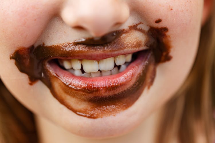 Close-up Of Smiling Child Mouth In Chocolate