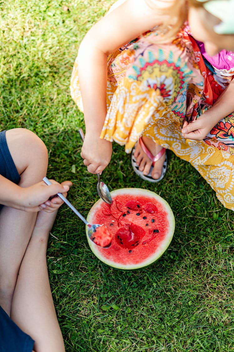 People Sitting And Eating Watermelon With Spoon