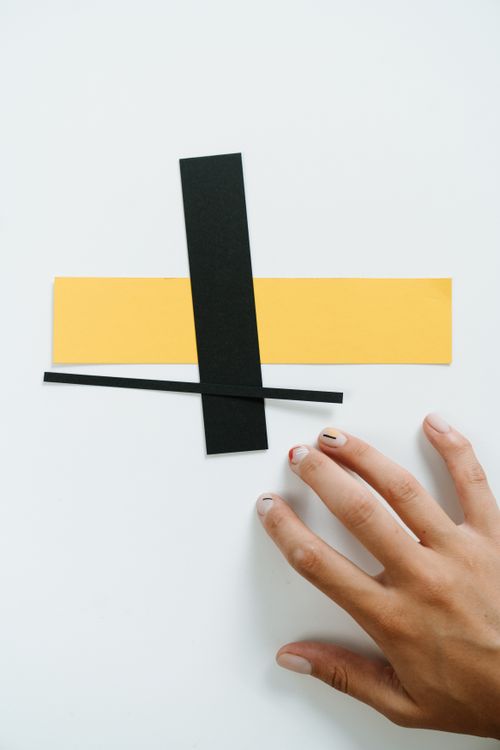 Free Geometric abstract art with black and yellow paper shapes and a hand. Stock Photo