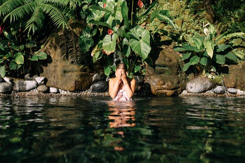 Free Woman in Lake Covering Face with Hands Stock Photo